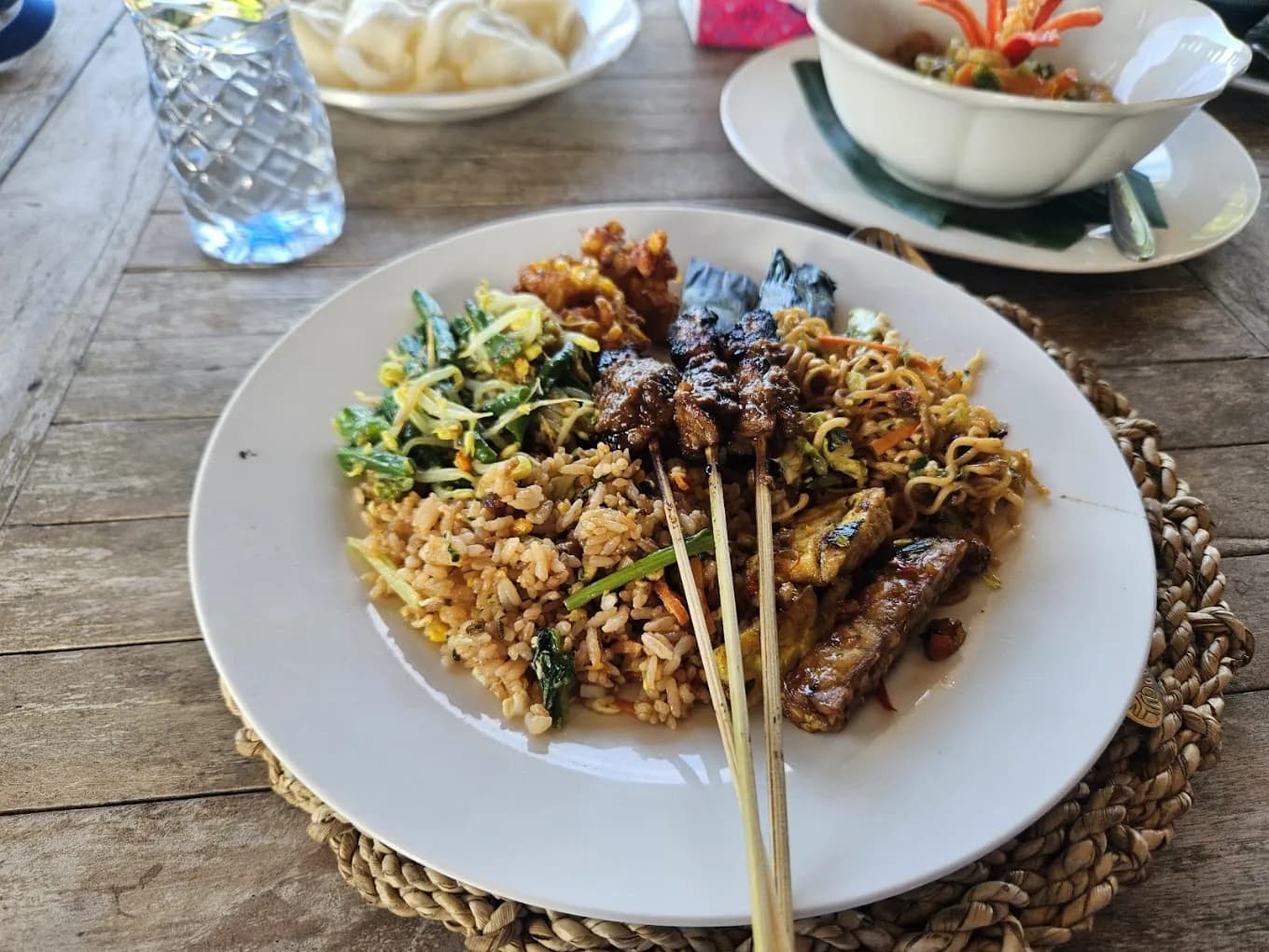 A class plate of nasi goreng, sate lilit on lemongrass, corn fritters, and sambal at Warung Tumang Bali, from the Petulu class where tipat is cooked