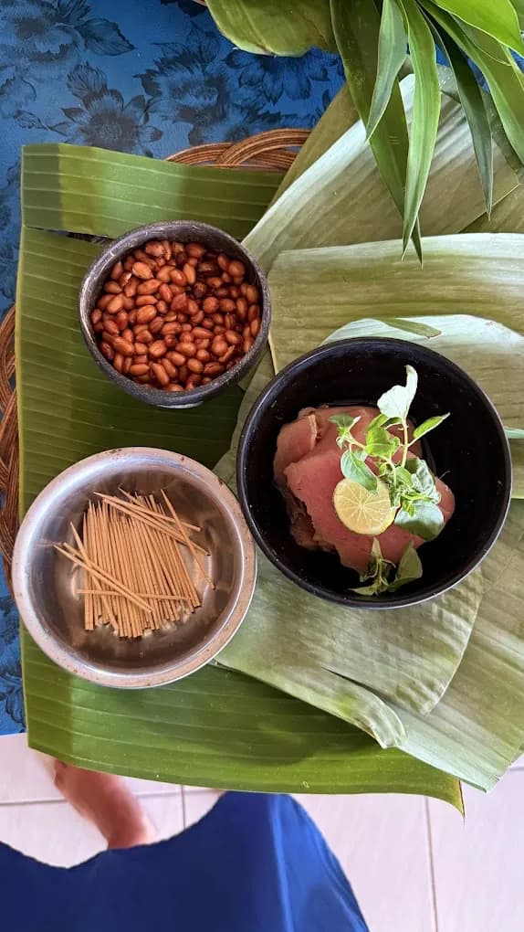 Satay sticks, roasted peanuts, and grilled meat on a banana leaf in Petulu, from the Petulu class where ayam betutu is cooked