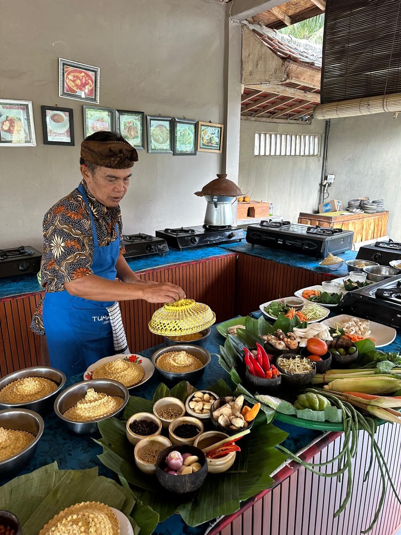 A wooden table set with bowls of ground spices, chilies, grated coconut, and banana leaves